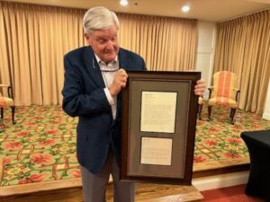 Picture of Tom Efird holding framed letter about Covenant Village